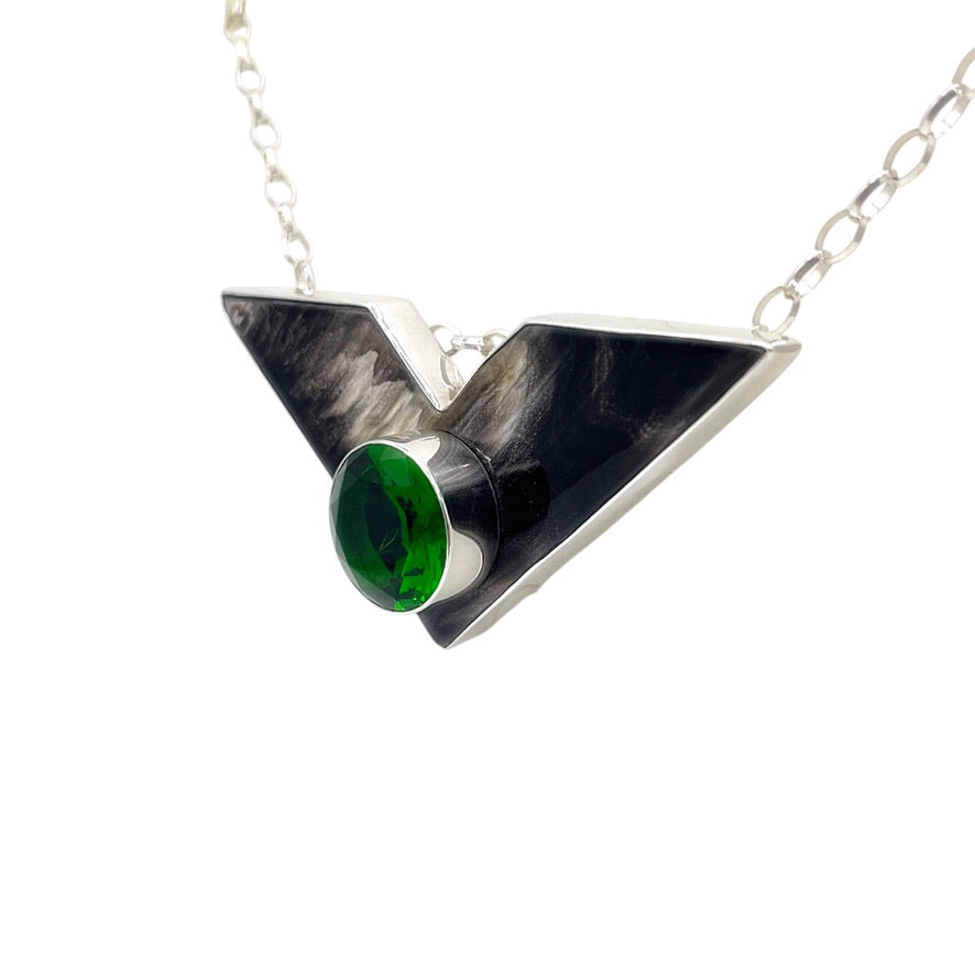 Angled view of buffalo horn and emerald green volcanic glass pendant in sterling silver